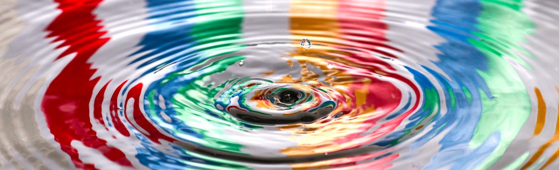 A drop striking coloured water, sending out concentric rings